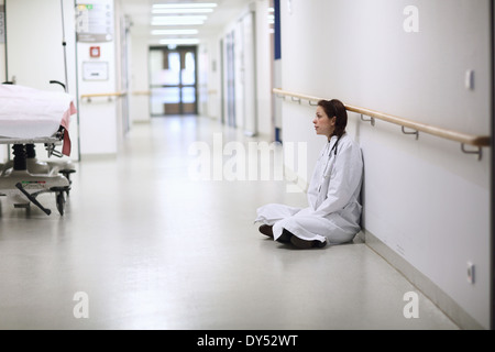 Ärztin im Krankenhausflur Schneidersitz sitzen Stockfoto