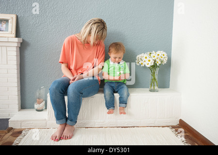 Junge Frau und Baby Boy mit Blumen spielen Stockfoto