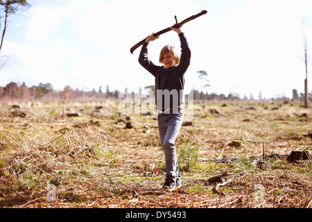 Junge hält einen Stock in einer Plantage Lichtung Stockfoto