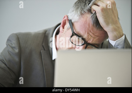 Gestresste reifer Geschäftsmann im Büro Stockfoto