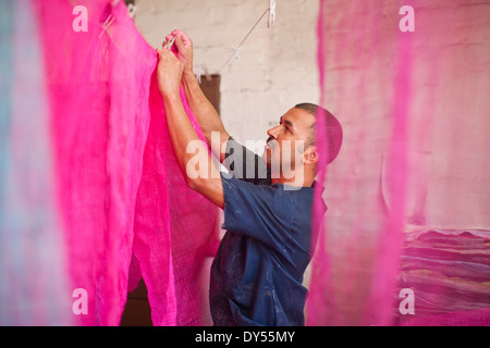 Mann aufhängen gefärbten Stoff in traditioneller Hutmacher workshop Stockfoto