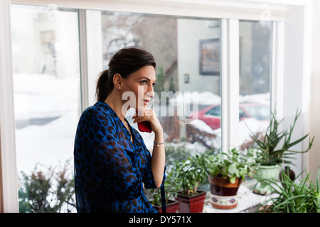 Junge Frau im Wohnzimmer halten Handy Stockfoto