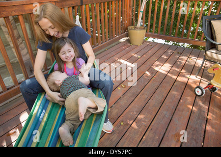 Mutter und Kinder spielen auf der Hängematte Stockfoto