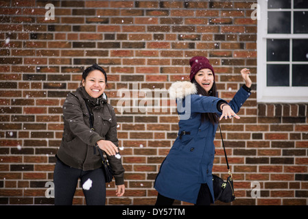 Zwei man adulte Weibchen werfen Schneebälle Stockfoto