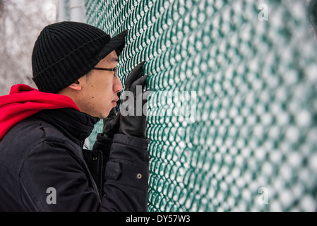 Porträt des jungen Mannes auf der Suche durch Park Zaun bei-30 Grad Celsius Stockfoto