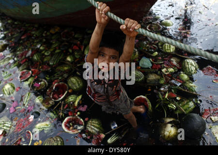 Dhaka, Bangladesch. 7. April 2014. Eine Straße junge Suche nach essbaren Wassermelonen vom Fluss Buriganga verschmutzt und verdreckt. Stoßstange Produktion der Wassermelone in Bangladesch in dieser Saison. Experten sagten, dass die gute Qualität Wassermelonen waren eine Rekordernte in diesem Jahr wegen Begünstigung Wetter und Landwirtschaft verbessert. Zakir Hossain © Chowdhury/NurPhoto/ZUMAPRESS.com/Alamy Live-Nachrichten Stockfoto