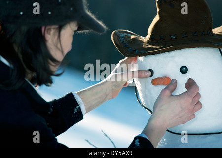 Reife Frau, die Platzierung der Augen auf einen Schneemann-Gesicht Stockfoto