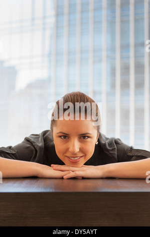 Porträt der jungen Unternehmerin vornübergebeugt auf Schreibtisch Stockfoto