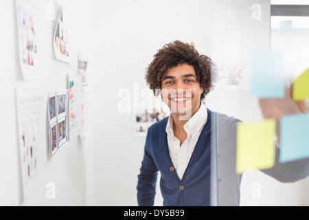 Junger Mann mit Klebstoff Noten, Lächeln Stockfoto