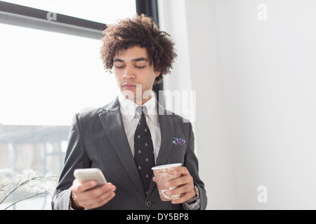 Junger Mann mit Handy mit Kaffee Stockfoto