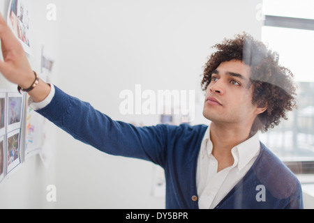 Junger Mann, Blick auf Bilder an Wand Stockfoto