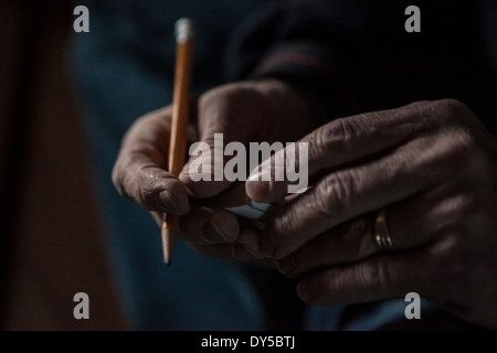 Nahaufnahme von männlichen Händen hält einen Bleistift und ein Stück Holz Stockfoto