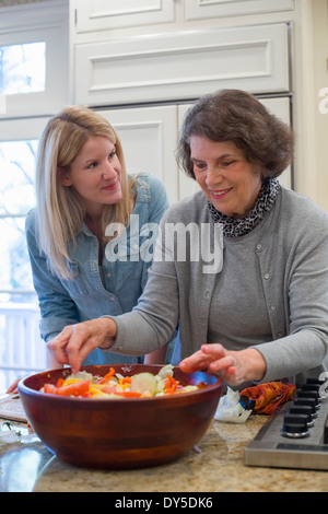 Ältere Frau und Enkelin Vorbereitung Salatschüssel Stockfoto