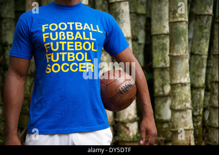 Brasilianischer Fußballspieler trägt internationalen Fußball-Trikot vor dem tropischen Bambus-Wald-Hintergrund Stockfoto