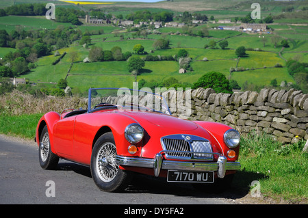 Ein MGA-Sportwagen steht auf einem Feldweg im Sommer mit einem englischen Dorf auf dem Hügel im Hintergrund Stockfoto
