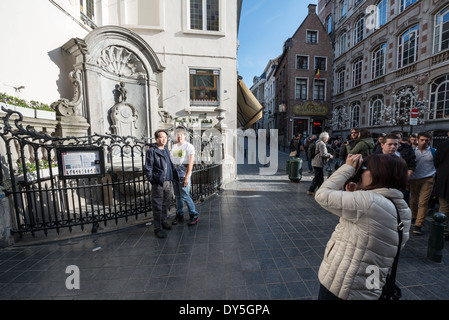 Manneken Pis Brunnen Touristen Brüssel Belgien / BRÜSSEL, Belgien — Touristen posieren für Fotos vor dem Manneken Pis Brunnen an der Ecke Rue de l'Etuve und Rue du Chêne. Der konvexe schmiedeeiserne Grill, der 1851 von Robie und Vanderrest unter dem Architekten Joseph Poelaert entworfen wurde, schützt eine Nachbildung der ursprünglichen Bronze von Jérôme Duquesnoy dem Älteren aus dem Jahr 1620. Die authentische Skulptur wurde nach dem Diebstahl im Jahr 1965 in das Brüsseler Stadtmuseum im Maison du ROI auf dem Grand-Place verlegt. Stockfoto