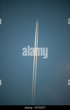 Flugzeug-Kondensstreifen vor dem Himmel | BRÜSSEL, Belgien — Ein Düsenflugzeug zieht zwei Kondensstreifen über einen klaren Abendhimmel über Brüssel, während die untergehende Sonne seine Auspuffschwaden einfängt. Kondensstreifen entstehen, wenn heißer, feuchter Motorabgas auf kalte Höhenluft trifft und zu sichtbaren Eiskristallstreifen gefriert, die je nach Luftfeuchtigkeit für Minuten oder Stunden anhalten können. Stockfoto