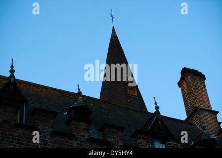 BRÜGGE, Belgien – Ein mittelalterlicher Turm und eine historische Dachlinie auf dem Burgplatz von Brügge stehen vor dem Himmel vor der Dämmerung. Die architektonischen Details dieses historischen Bauwerks zeigen die raffinierten Designelemente, die typisch für die mittelalterliche flämische Architektur sind. Das Licht am frühen Morgen unterstreicht das unverwechselbare Profil dieses bedeutenden Gebäudes auf einem der wichtigsten historischen Plätze von Brügge. Stockfoto