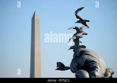 ARLINGTON, Virginia, Vereinigte Staaten – der obere Teil des Navy-Merchant Marine Memorial mit seinen Alu-Möwen und Wellen, die sich am Washington Monument auf der anderen Seite des Potomac River befinden. Die skulpturalen Formen des Art déco-Denkmals schaffen eine dramatische Komposition mit dem ikonischen Obelisken im Hintergrund, der die maritimen Tribut in Arlington mit den Denkmälern des nationalen Einkaufszentrums verbindet. Stockfoto