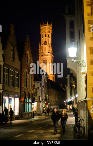 Eine nächtliche Szene einer der Straßen der historischen Altstadt von Brügge, Belgien. Der beleuchtete Glockenturm im Hintergrund ist eines der bekanntesten Wahrzeichen der Stadt. Der Glockenturm (Belfort) ist ein mittelalterlicher Glockenturm stehend über den Markt in der Altstadt von Brügge. Die erste Stufe wurde im Jahre 1240 mit weiteren Etappen am oberen Ende des 15. Jahrhunderts erbaute gebaut. Stockfoto