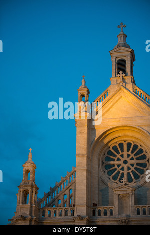 Fluter fangen die Vorderfassade des Église Sainte-Catherine de Bruxelles (Kirche von Str. Catherine von Brüssel) gegen den dunkelblauen Himmel der Dämmerung. Die Kirche in der Innenstadt von Brüssel, wurde zwischen 1854 und 1874 erbaut und befindet sich an einem Ende der Place Ste Catherine. Stockfoto