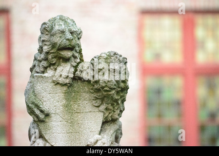 Heraldic Lions Stone Carving Brügge Belgien / BRÜGGE, Belgien — Ein Paar heraldischer Steinlöwen mit einem Schild steht als dekorative architektonische Elemente im historischen Zentrum Brügge. Diese skulpturalen Figuren repräsentieren traditionelle Bürgersymbole, die in mittelalterlichen europäischen Städten üblich sind. Die Löwen demonstrieren die raffinierte Steinschnitzertradition, die zum architektonischen Erbe von Brügge beigetragen hat. Stockfoto