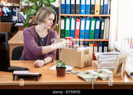 Gebrannte Frau sammeln von Dingen im Karton am Arbeitsplatz Stockfoto