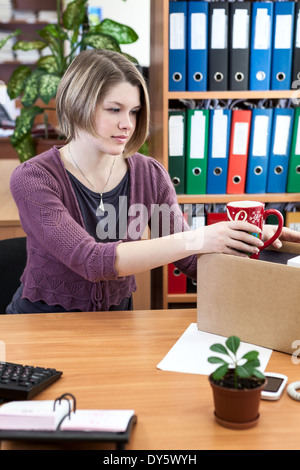 Frau sammelt Dinge in einem Karton am Arbeitsplatz Stockfoto