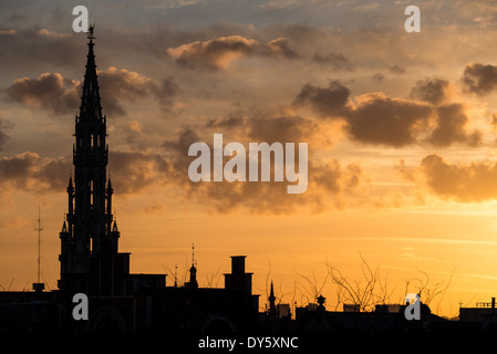 BRÜSSEL, Belgien – die Silhouette der Brüsseler Skyline bei Sonnenuntergang vor einem goldenen Himmel mit einigen Wolken. Der hohe Turm des Brüsseler Rathauses (Hotel de Ville) ist 96 Meter entfernt. Stockfoto