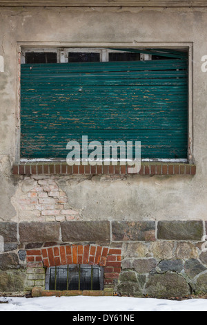 Türkisfarbene Fensterläden auf einem verfallenen alten Haus im Winter Europa gebrochen. Stockfoto