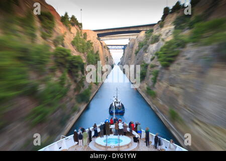 Touristen auf dem Bogen eine kleine Kreuzfahrt Schiff gezogen von einem Schlepper am frühen Morgen Transit der Kanal von Korinth, Griechenland, Europa Stockfoto