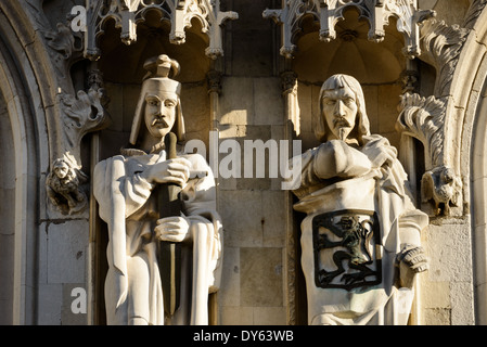 Statuen des Stadt halls von Brügge Brügge Belgien | BRÜGGE, Belgien — Eine Nahaufnahme von zwei gepanzerten und gewandeten Statuen in Nischen an der Fassade des Stadthauses von Brügge zeigt die geschnitzten Löwen und schildtragenden Figuren, die das mittelalterliche Bildprogramm des Stadt halls flankieren. Mit dem Bau im Jahr 1376 gilt das Stadthaus als das älteste seiner Art in den Niederlanden, und seine Nischenstatuen wurden entworfen, um die Grafen von Flandern und verbündeten Adel darzustellen. Kleine geschnitzte Löwen sitzen neben den Figuren als heraldische Wappen der Grafschaft. Stockfoto