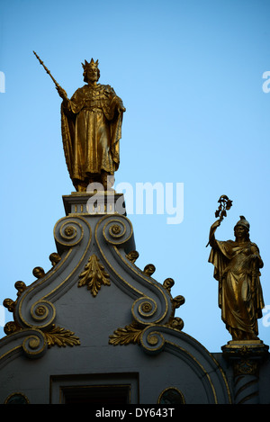 BRÜGGE, Belgien — Eine vergoldete Statue eines Königs krönt das Oude Griffie (altes Blockflötenhaus) auf dem Burgplatz. Dieses historische Bürgergebäude aus dem Mittelalter verfügt über eine aufwendige architektonische Dekoration, darunter diese prominente goldene Figur. Das Gebäude repräsentiert die raffinierte Mischung aus gotischen und Renaissance-Stilen, die für die Bürgerarchitektur Brügge charakteristisch sind. Stockfoto