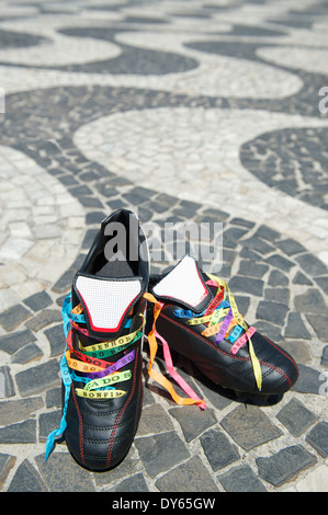 Viel Glück Fußballschuhe Fußball geschnürte mit brasilianischen Wunsch Bändern auf dem Bürgersteig Copacabana Strand Rio De Janeiro Fußball-Stollen Stockfoto