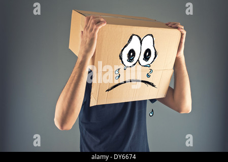 Mann mit Karton auf den Kopf und traurig weinende Gesichtsausdruck. Konzept der Traurigkeit und Depression. Stockfoto