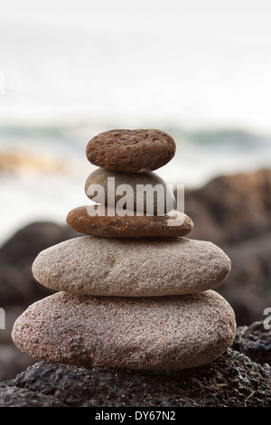 Steinen Pyramide auf Sand als Symbol für Zen, Harmonie und Balance. Ozean im Hintergrund Stockfoto