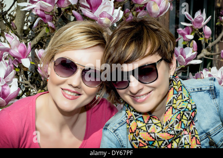 Zwei junge kaukasischen Frauen posieren mit blühenden Magnolie. Frauen Beauty &amp; Fashion. Stockfoto