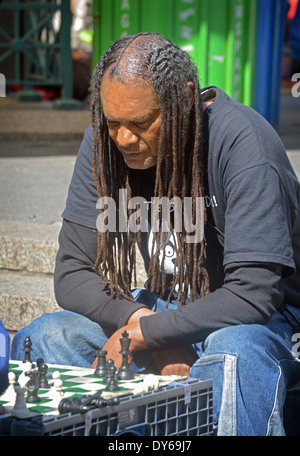 Ein Schachspieler mit lange Dreadlocks, die Konzentration während des Spiels im Union Square Park in Manhattan, New York City Stockfoto