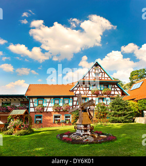 Typisches traditionelles Haus im Schwarzwald, Süddeutschland. europäische Landschaft mit Blumen Garten und bewölkten blauen Himmel Stockfoto