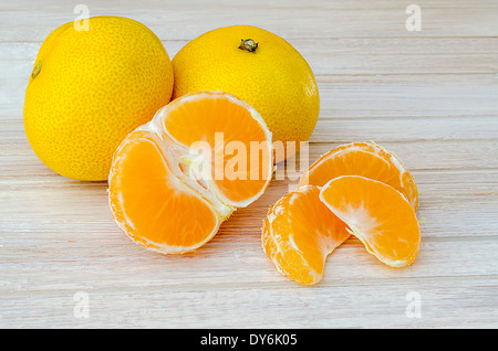 Gruppe von Mandarinen, geschält und in Segmente auf dem weißen Küchentisch aufgeteilt Stockfoto