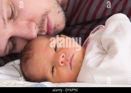 Zugeschnittenes Bild des Vaters, der sich mit seinem neugeborenen Mädchen im Kuscheln auflegt Stockfoto