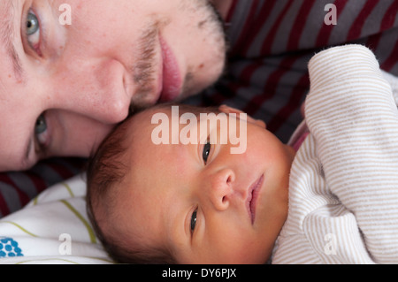 Zugeschnittenes Bild des Vaters, der sich mit seinem neugeborenen Mädchen im Kuscheln auflegt Stockfoto