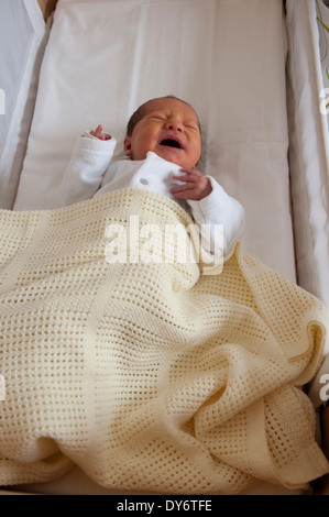 Neugeborenes Babymädchen liegen in ihrer Krippe weint Stockfoto