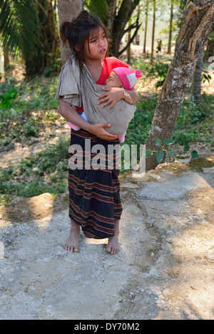 Hmong Stammkind trägt ein Baby in einer Schlinge in einem Dorf am Mekong Flussufer in Laos, Lao, Südostasien Stockfoto