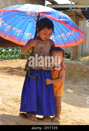 Zwei Hmong Stammes Dorf Kinder halten einen Sonnenschirm in einer Gemeinschaft entlang der Mekong Flussufer, Laos, Lao, Südostasien Stockfoto