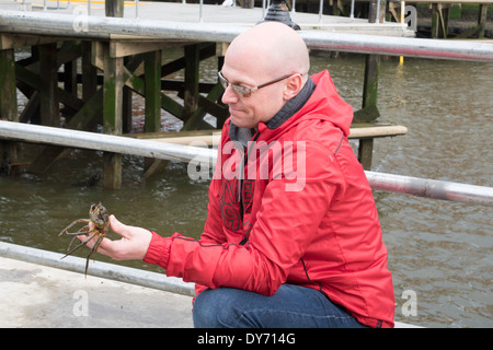 Mann mit einer Krabbe gefangen, während die Brücke im Hafen von Whitby North Yorkshire England mit seiner Familie Fischen Stockfoto