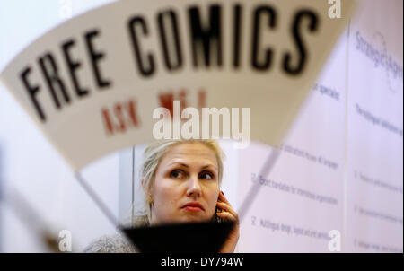 London, UK. 8. April 2014. Eine Frau wird während der London Book Fair in London, UK, 8. April 2014 hinter ein Plakat gesehen. 3 Tage London Book Fair startete am Dienstag. Bildnachweis: Yin Gang/Xinhua/Alamy Live-Nachrichten Stockfoto