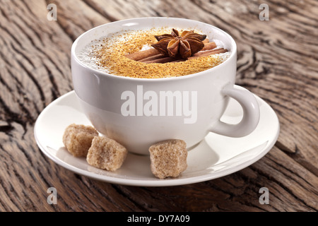 Tasse Cappuccino mit Gewürzen und Würfel aus braunem Zucker in seiner Nähe eingerichtet. Stockfoto