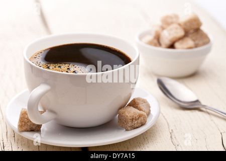 Tasse Kaffee mit Würfelzucker auf alten Holztisch. Stockfoto