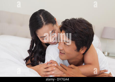 Glückliches Paar zusammen auf Bett liegend Stockfoto